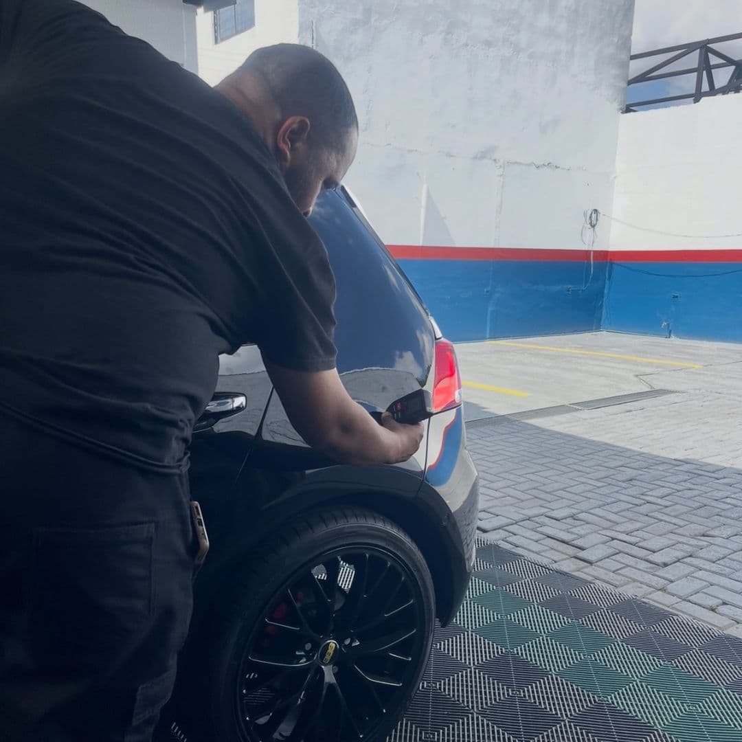 Perito da Maxilaudo aplicando o medidor de camada de tinta na traseira de um veículo