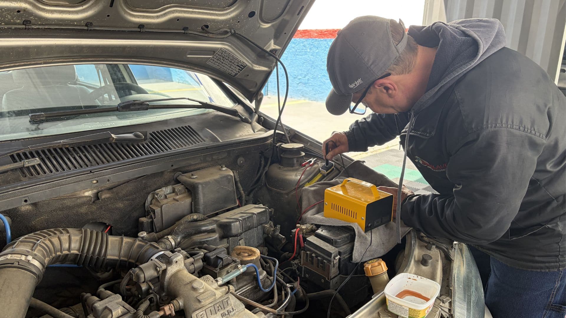 Técnico da Maxilaudo operando o equipamento de gravação no compartimento do motor de um veículo